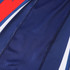 A close-up of a blue long-sleeved t-shirt featuring red and white accents, with a textured fabric. It has a logo.