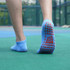 Low cut gripper socks in light blue with red non-slip grip pattern on the soles, on a person’s feet.