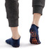 Low cut kids gripper socks in navy blue with orange grip dots on the sole, displayed from the back on a model's feet.