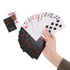 A hand holding playing cards, featuring a mix of numbers and suit symbols, with a deck in the background.