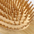 A small bamboo hairbrush featuring rounded bamboo bristles arranged on a textured base. It has a natural finish.
