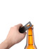 A drink bottle opener shaped like a card, in a sleek black finish, being used to open a beer bottle.