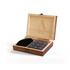 A wooden box containing grey whiskey stones, a pair of tongs, and a black storage pouch, featuring a logo on the lid.
