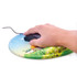 A round gel mouse mat featuring a colourful landscape design with a house and greenery, with a hand using a mouse on it.