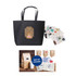 A black paper bag with handles featuring a design and an assortment of stickers in various colours.