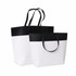 A small black and white paper bag with a black top and white bottom, featuring sturdy handles.