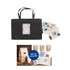 A black paper bag with knitted handles, accompanied by decorative stickers and a sample coffee bag.