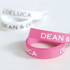 Ribbed fabric ribbons in pink and white, featuring text and a logo. Each ribbon is 22mm in width.