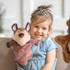 A plush wolf hand puppet in brown and beige, held by a smiling child sitting on a couch.