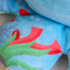 A blue keyring featuring a plush animal design with colourful patterns of red and green elements.