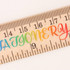A wooden ruler featuring a dual scale and a colourful gradient design. It has a logo present on the surface.