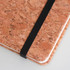A5 cork notebook with a natural cork exterior and a black elastic band, featuring a simple white edge.