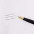 A black plastic click pen with a gold tip beside three lines drawn on white paper. The pen features branding.