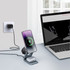 A foldable wireless charger stand in grey, charging a phone and earbuds, placed next to a laptop.