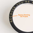 A custom-shaped mirror phone pop holder with a black frame and an epoxy domed finish. It features a logo on the edge.