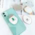 A custom-shaped mirror phone pop holder in various colours, featuring a logo on one design, placed on a mint phone.