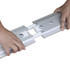 A pair of hands assembling a silver LED light box frame with connectors.
