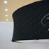 A round hanging banner in black fabric featuring a subtle pattern and a logo printed on it, suspended from the ceiling.