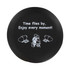 A round black stress reliever featuring a design of two seated figures and an inspirational message in white text.