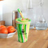 A drink tumbler in green, pink, and yellow with a straw and a logo, placed on a wooden counter.