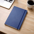 A navy blue journal with a textured cover, placed on a wooden desk next to a laptop and a cup of coffee.