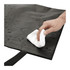 A hand wipes a wet surface of a black double laminated tote bag, showcasing its wipeable feature.