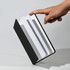 A Polychroma A5 notebook with a black cover and white pages, being held by a hand, showcasing its design.