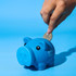 A blue piggy bank with cartoonish features, being fed a coin. It has a logo on its side.