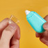 A turquoise glue tape dispenser with a white tip, held alongside a clear protective cap.