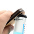 A drink bottle opener key ring made of bamboo, being used to open a glass bottle with a black cap.