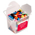 A frosted noodle box filled with colourful choc beans, featuring a branded sticker on the side.