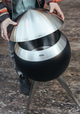 a man placing the Höfats MOON 45 Brushed Stainless Steel Cover on the outdoor fire pit by hofats