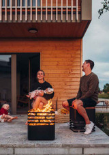 outdoor fire lit in the Höfats CUBE BBQ Set with a couple enjoying the evening