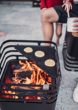cooking outdoors making small pancakes on the Höfats CUBE Plancha – Enameled Cast‑Iron Griddle Plate