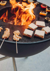 Party food grilling outdoors on the bowl 70 fire pit using the plancha