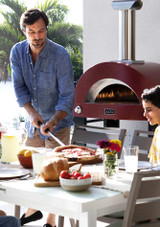 a man serving a pizza from his Alfa Forni Moderno Pizza Oven