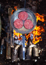 Petromax Wrought Iron Pan SP32 – 25 cm base round pan with extended wrought iron handle, shown in use cooking beef burgers.