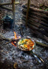 Petromax Wrought Iron Pan SP28 – 28 cm diameter pan with welded iron handle, shown in use cooking on embers.