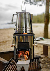Petromax Rocket Stove RF33 – compact stainless steel rocket stove with cast-iron cooking top and wooden handles, shown in use boiling a kettle. Petromax Rocket Stove RF33 – compact stainless steel rocket stove with cast-iron cooking top and wooden handles, shown in use boiling a kettle.