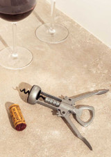 L’Atelier du Vin Le De Gaulle – wing-style lever corkscrew with raw zinc-finish body, on a table with wings open