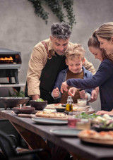 Family outdoors preparing a pizza for their Etna Fermo Pizza Oven Family outdoors preparing a pizza for their Etna Fermo Pizza Oven