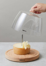 Boska Cheese Curler Amigo with Dome 850511 – beechwood base, stainless blade, and clear dome cover, with someone taking the lid off. Boska Cheese Curler Amigo with Dome 850511 – beechwood base, stainless blade, and clear dome cover, with someone taking the lid off.