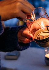 A woman light a candle in the Höfats Gravity Candle Lantern – Black