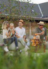Family sitting around an outdoor fire in the Höfats CUBE Fire Basket