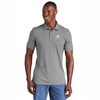 Model wearing a Travismathew Sunnyvale polo in dark grey heather with embroidered Watkins Wellness logo.