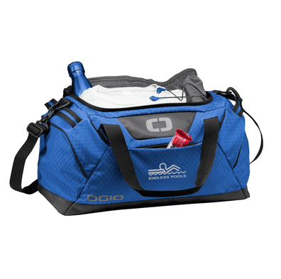 A Cobalt Blue OGIO Catalyst duffel bag with a CalderaSpas logo and adjustable straps.