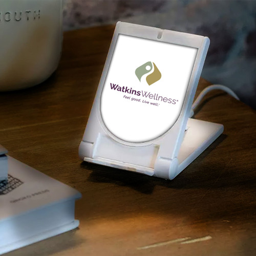 PowR Stand 2.0 Wireless Charging Pad with Watkins Wellness logo on a table.