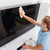 woman wiping television screen with cleaning cloth