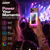 Pink magnetic wireless power bank with RGB light attached to a phone at a live concert