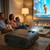 A family laughing while watching a bright animated movie projected on a large screen using the Laser LED projector.